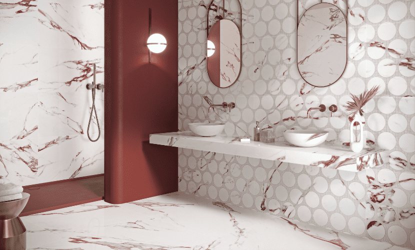 Baño de mármol rojo y blanco con ducha, lavabo y espejos redondos.