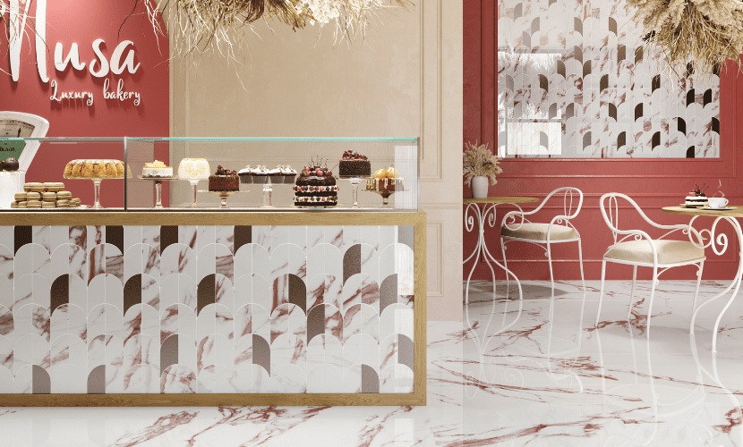 Interior de panadería con postres en vitrina, detalles de mármol rosa y blanco y zona de estar.