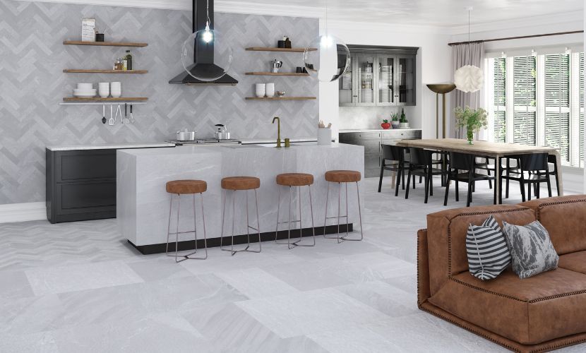 Cocina y sala de estar de concepto abierto con una gran isla, taburetes marrones y un sofá de cuero marrón.