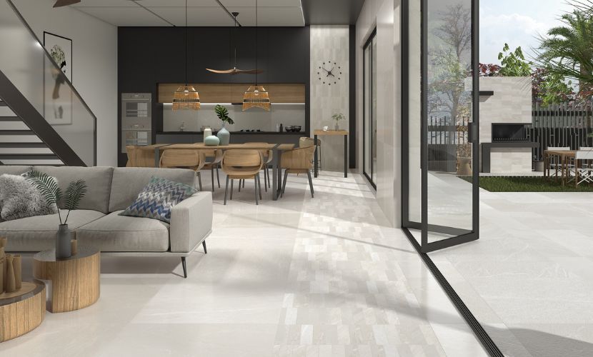 Moderna sala de estar con diseño abierto, pisos blancos y puertas corredizas de vidrio hacia un patio.