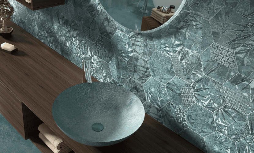 Baño con pared con diseño hexagonal en color verde azulado, tocador de madera con lavabo circular y espejo redondo.