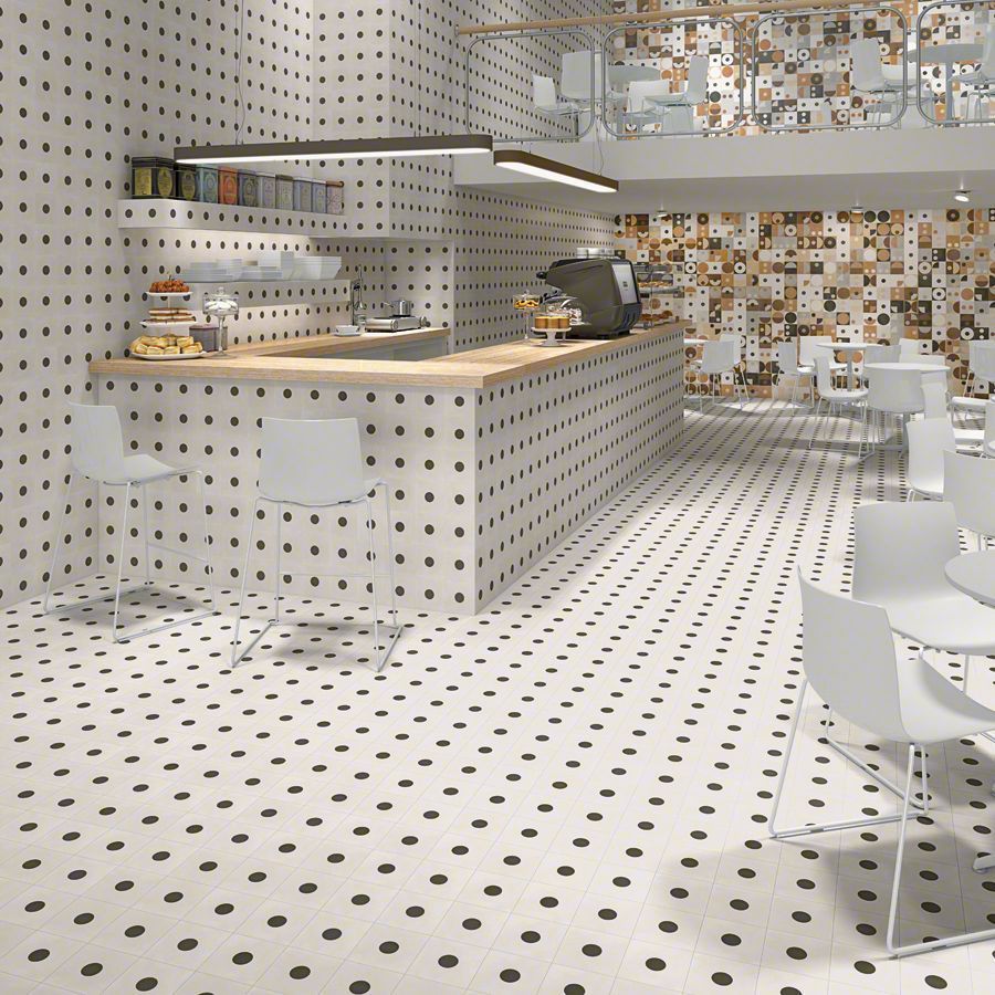 Interior de cafetería moderna con azulejos con patrón de puntos en las paredes y el piso; sillas y mostrador blancos.