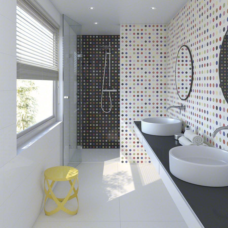 Baño moderno con azulejos blancos, negros y coloridos, dos lavabos y un taburete amarillo junto a una ventana.