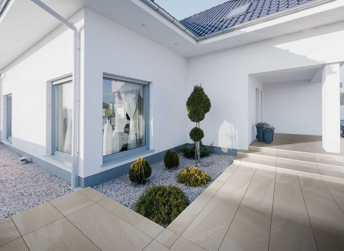 Exterior de casa blanca moderna con patio delantero ajardinado y pasarela de piedra.