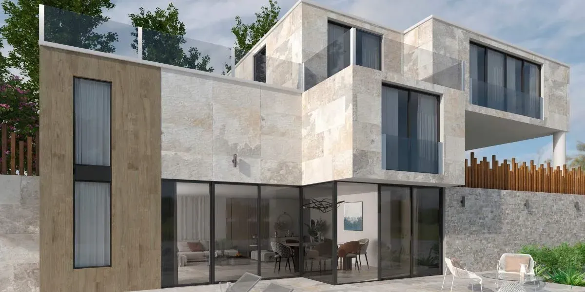 Moderna casa de varios pisos con fachada de piedra, grandes ventanales y balcón con barandilla de vidrio.