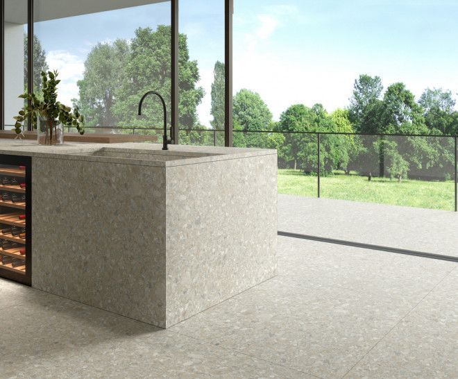 Isla de cocina moderna con fregadero y enfriador de vinos, con vista a un paisaje verde.