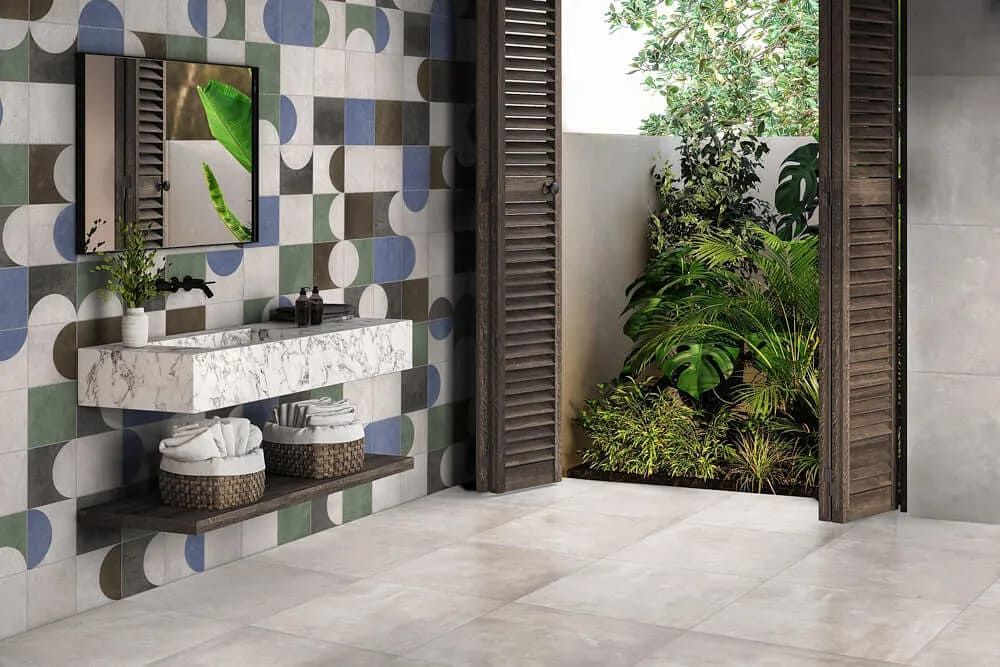 Baño con azulejos de pared estampados, lavabo de mármol y puerta abierta a la vegetación.