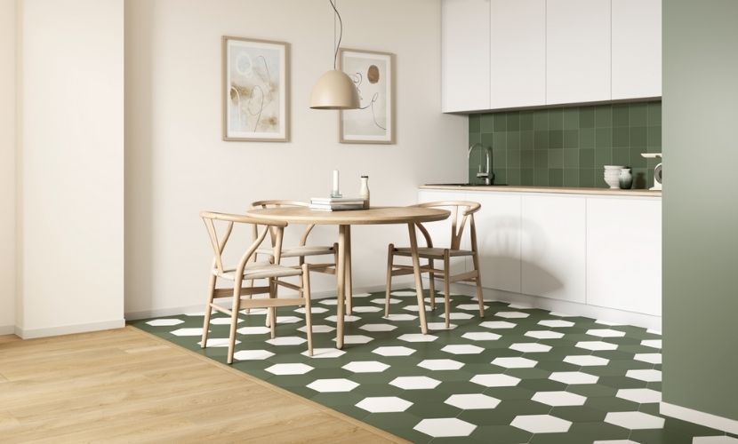 Área de comedor con mesa redonda, sillas, piso estampado, protector contra salpicaduras verde y gabinetes blancos.