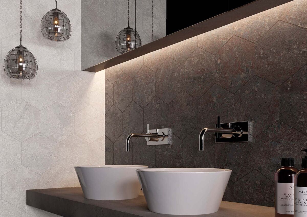 Baño moderno con dos lavabos blancos, azulejos de pared de color gris oscuro y lámparas colgantes.