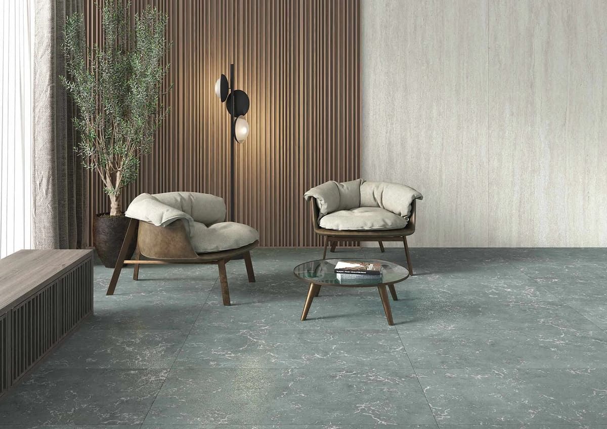 Sala de estar moderna con piso moteado azul, dos sillones, una mesa pequeña, una lámpara de pie y una planta alta en maceta.