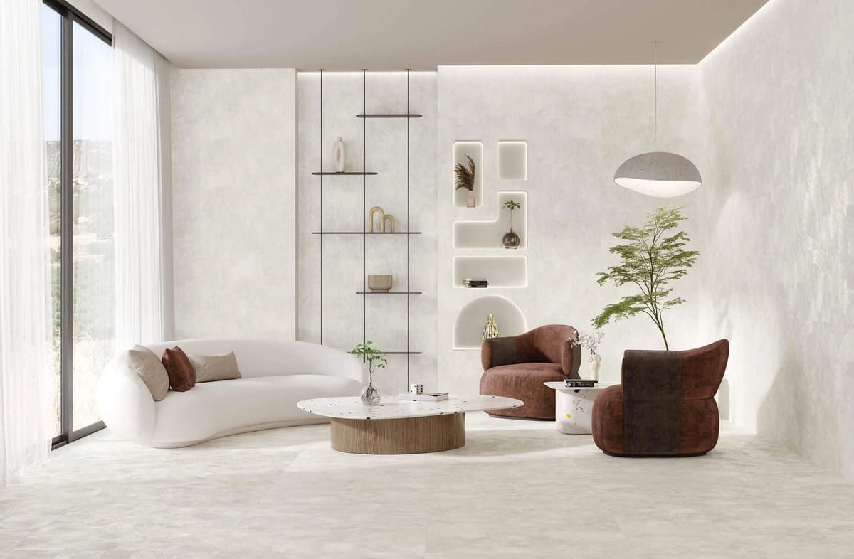 Sala de estar moderna con paredes blancas, sofá curvo, sillones marrones y estanterías decorativas.