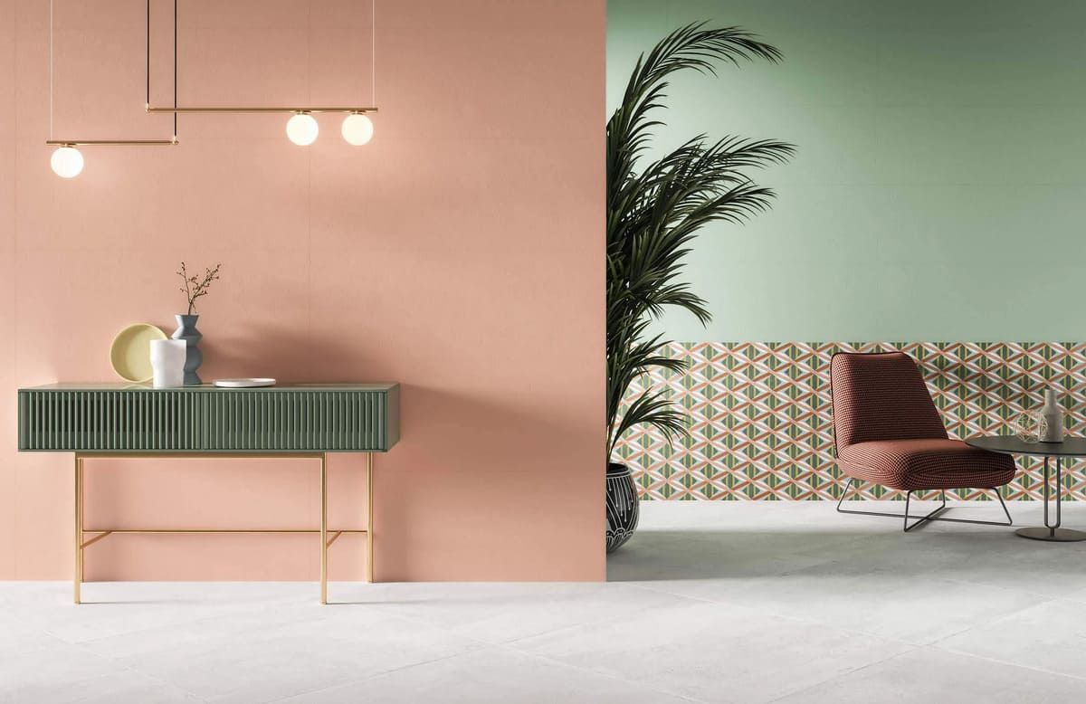 Habitación con paredes color melocotón y verde, que cuenta con una mesa consola, una silla y una planta grande.