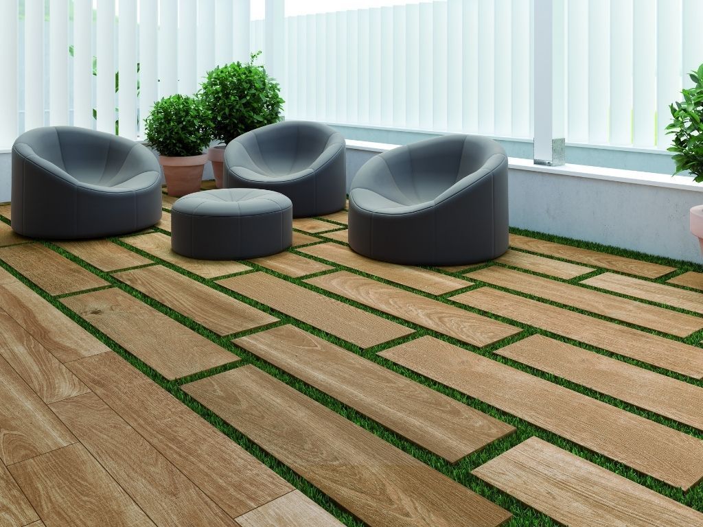 Patio con baldosas de apariencia madera y césped verde, con sillas y plantas grises.