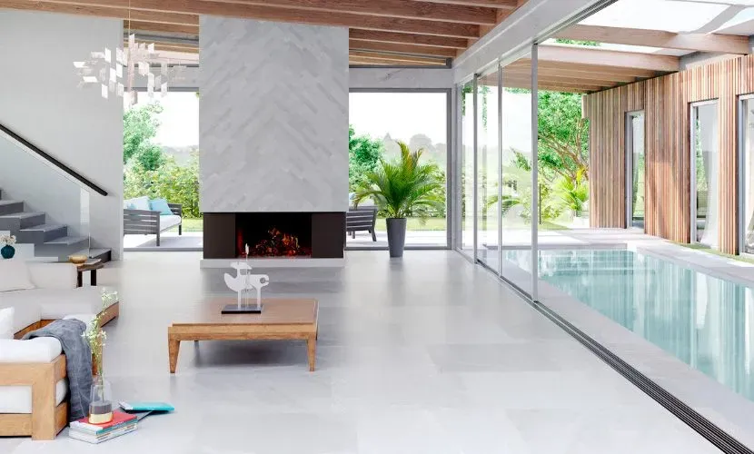 Moderno salón con chimenea, piscina y grandes ventanales con vistas a un jardín.