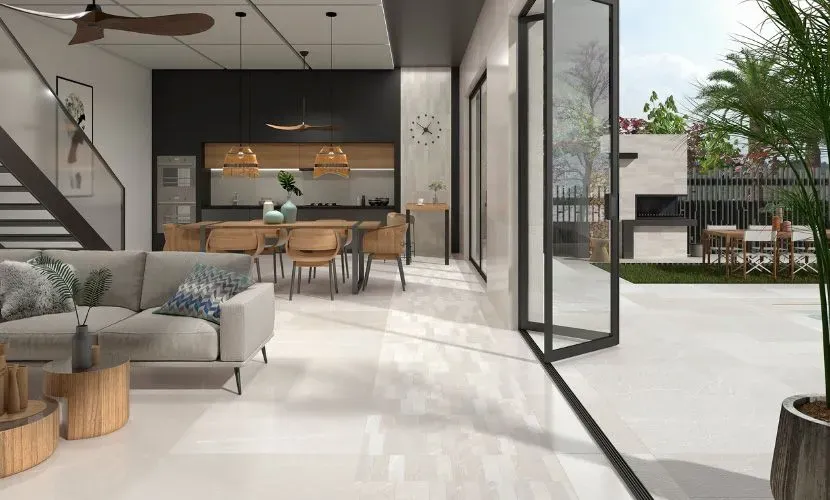 Moderna sala de estar abierta al patio; sofá gris, mesa de madera, comedor, vista al aire libre.