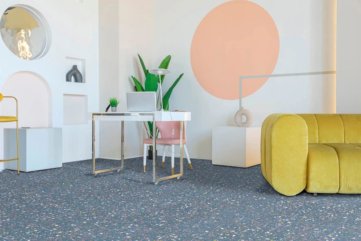 Un espacio de oficina moderno con un escritorio, un sofá amarillo y un gran círculo color durazno en la pared.