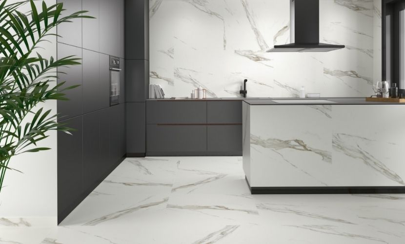 Cocina moderna con superficies con apariencia de mármol, gabinetes de color gris oscuro y campana extractora negra.