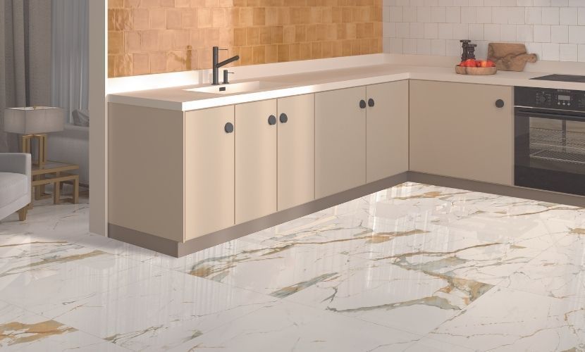 Cocina moderna con gabinetes beige, piso con apariencia de mármol y horno empotrado.