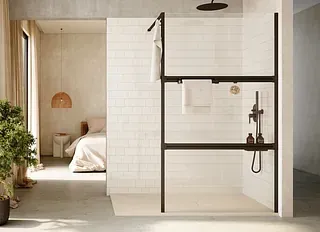 Baño moderno con ducha abierta, marco negro, azulejos blancos y vista al dormitorio.