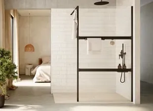 Baño moderno con ducha abierta, marco negro, azulejos blancos y vista al dormitorio.