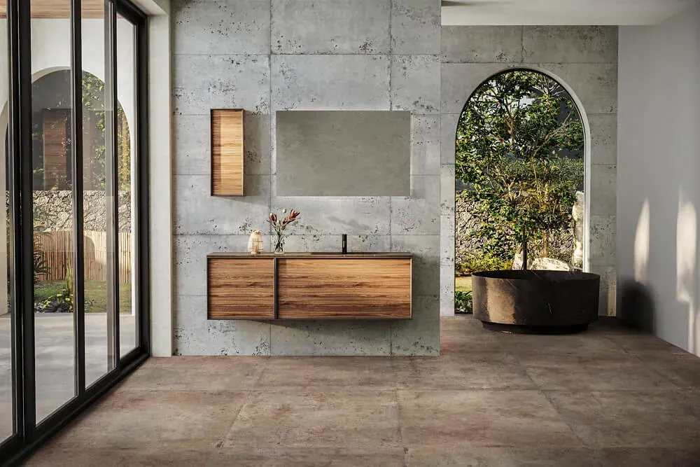 Baño moderno con tocador de madera, espejo grande y puerta arqueada con vista a la vegetación.