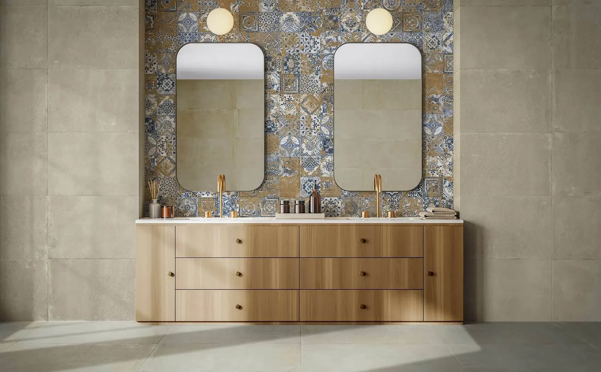 Baño con tocador de madera, pared con acento de azulejos estampados, dos espejos y accesorios dorados.