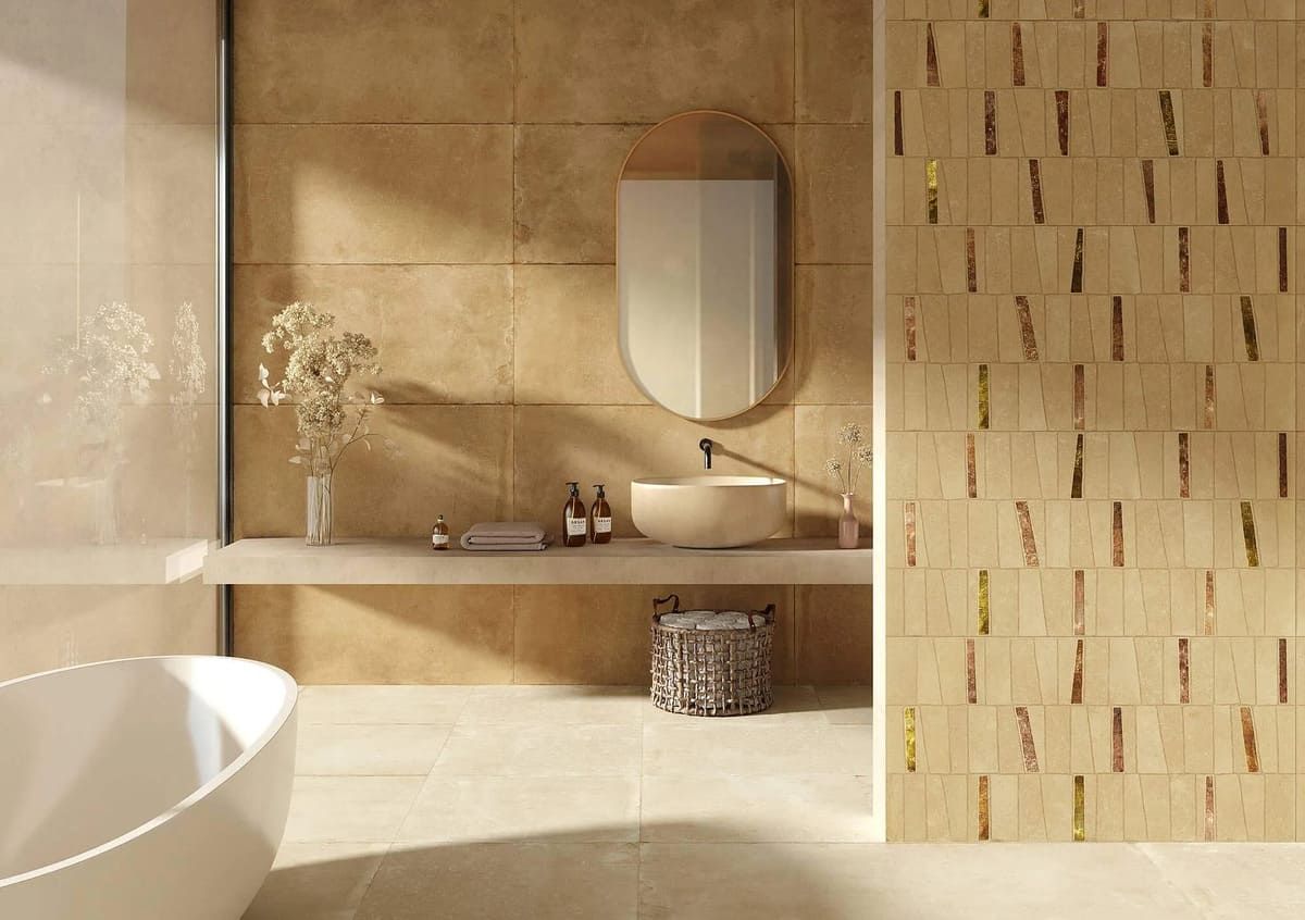 Baño con azulejos de piedra beige, espejo ovalado y pared con acento de madera.