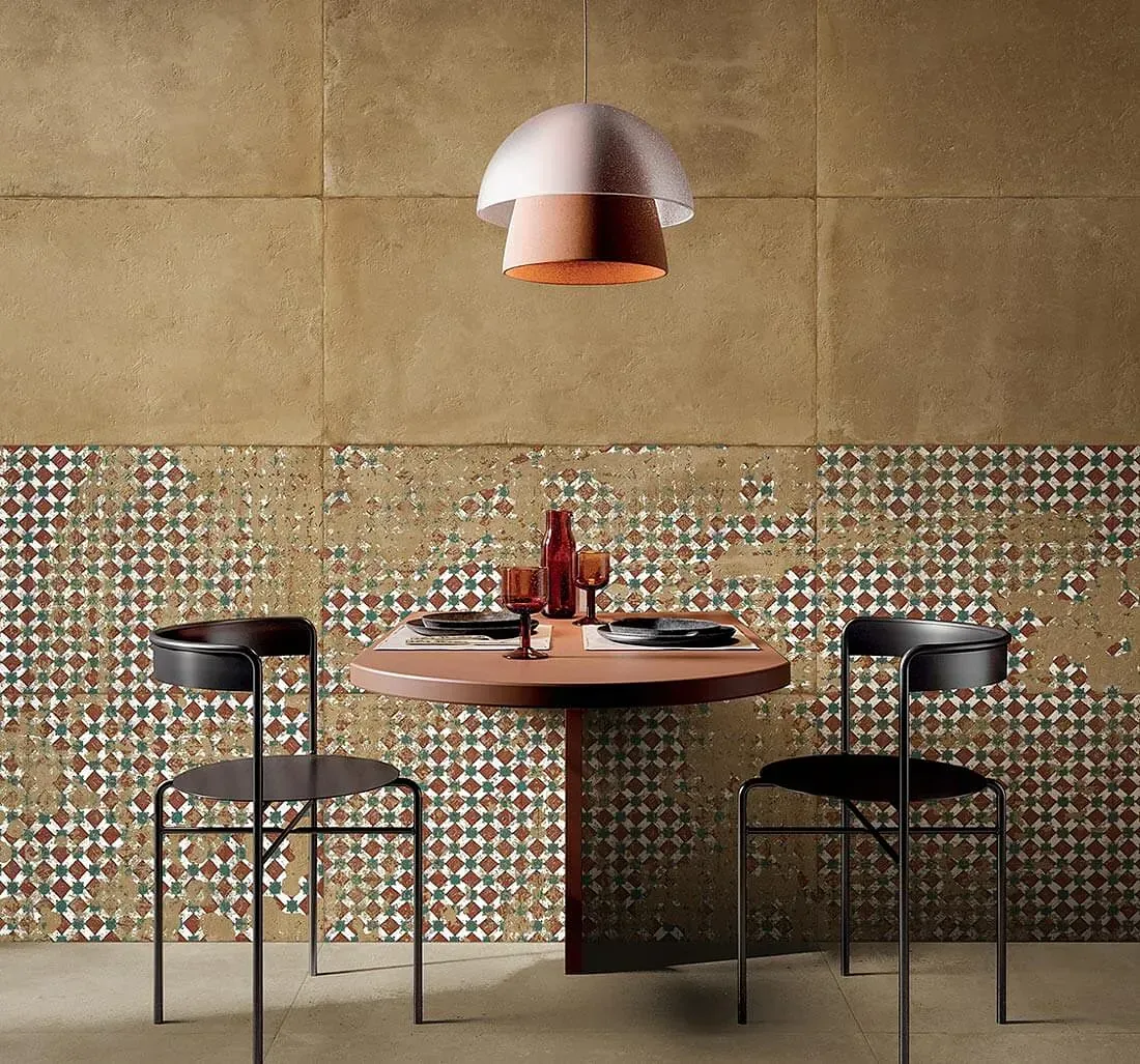 Comedor con mesa redonda, dos sillas, azulejos de pared estampados y lámpara colgante.