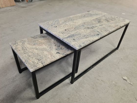 ein paar Tische mit Granitplatten und schwarzen Beinen