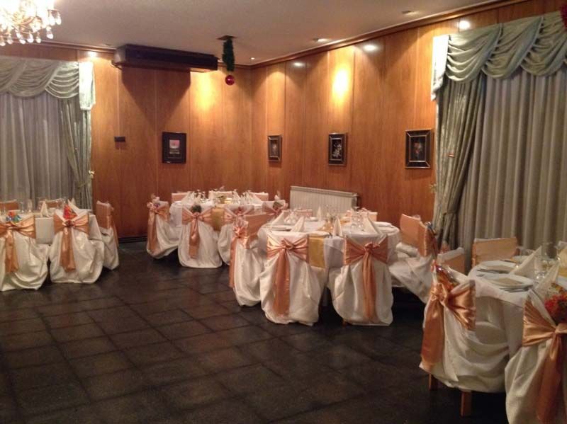 Elegante salón de banquetes con mesas redondas y sillas tapizadas en satén blanco y color melocotón.