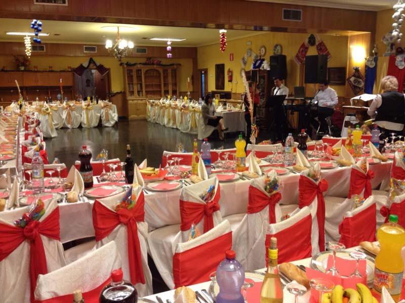 Salón de banquetes preparado con mesas y sillas decoradas en rojo y blanco para un evento formal.