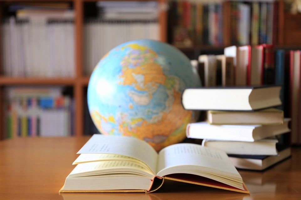 Globus und gestapelte Bücher auf einem Schreibtisch