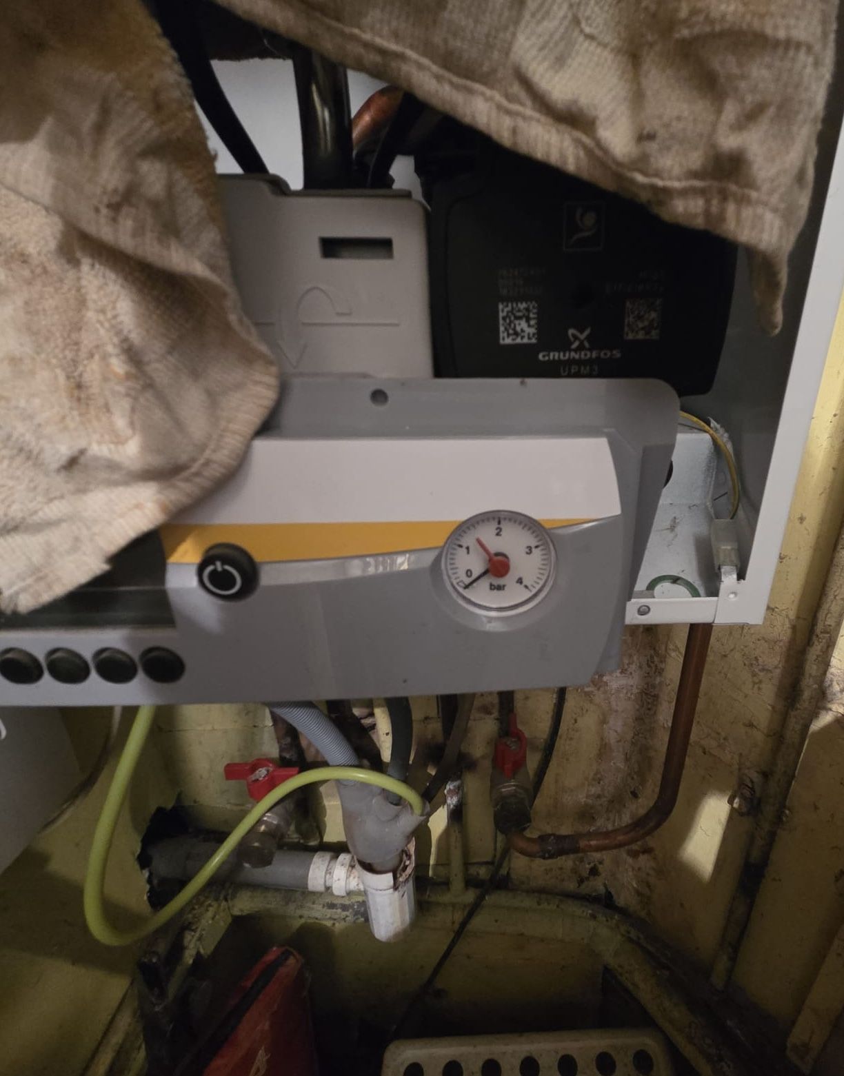 Gros plan sur une chaudière ou un appareil de chauffage avec tuyaux, manomètres et isolation apparente dans un local technique