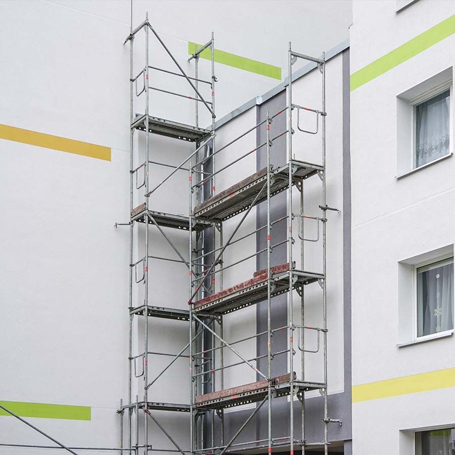 Andamio fijado a un edificio blanco y gris para trabajos de construcción o mantenimiento.