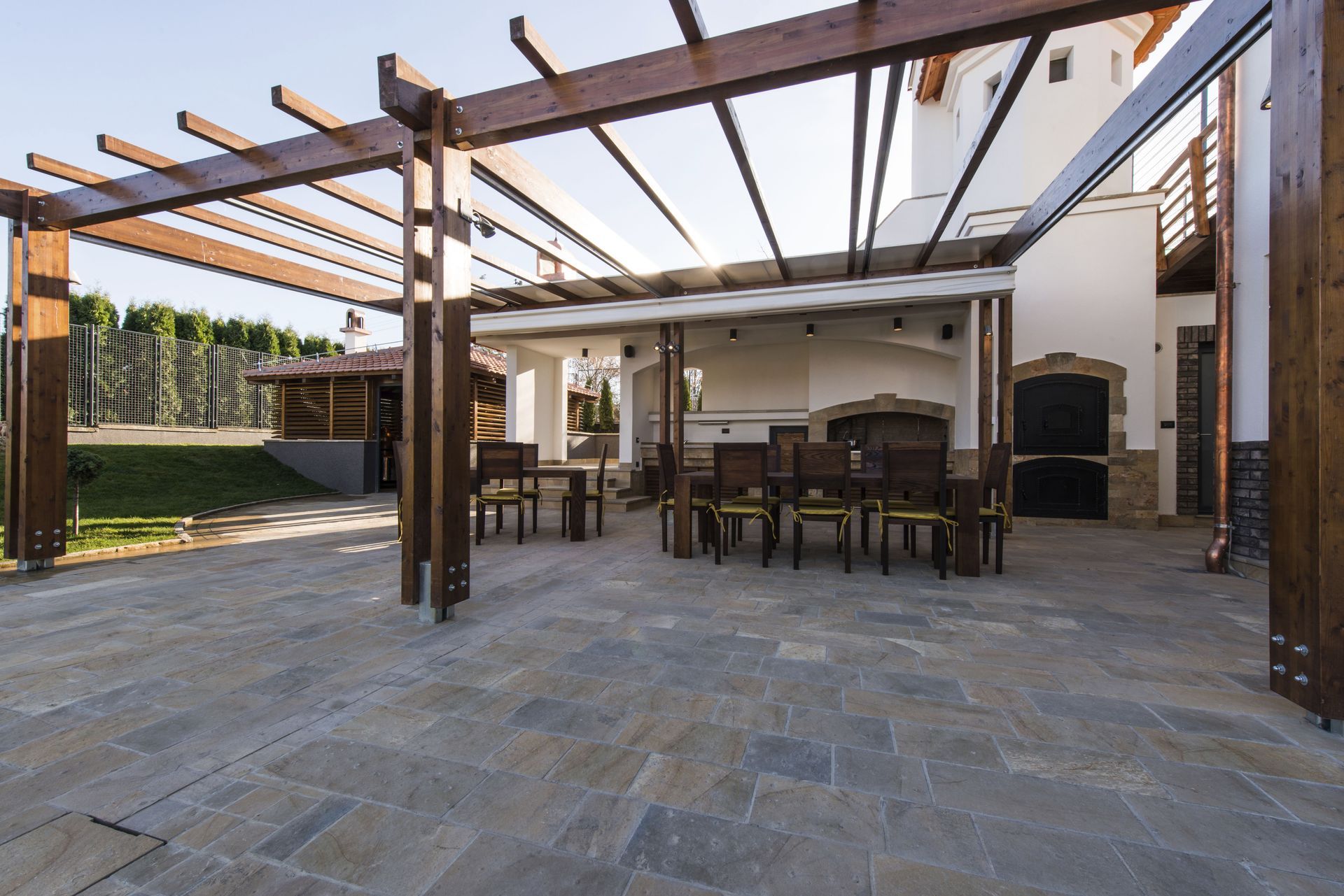 Un patio con una mesa y sillas debajo de una pérgola.