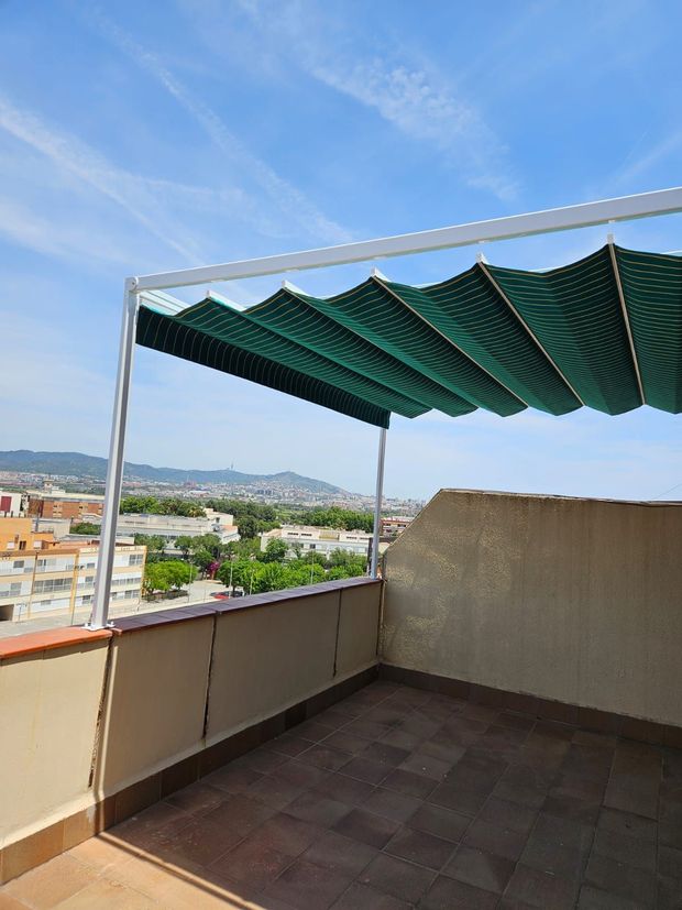 Un balcón con un dosel verde con vistas a una ciudad.