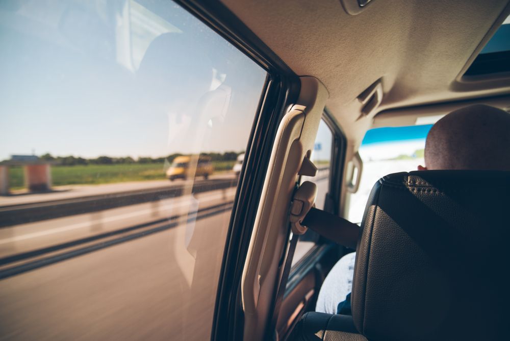 Un hombre está sentado en un coche mirando por la ventana.