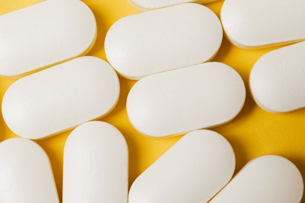 Un primer plano de pastillas blancas sobre una superficie amarilla.