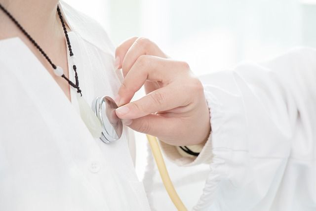 Un médico utiliza un estetoscopio para escuchar los latidos del corazón de un paciente.