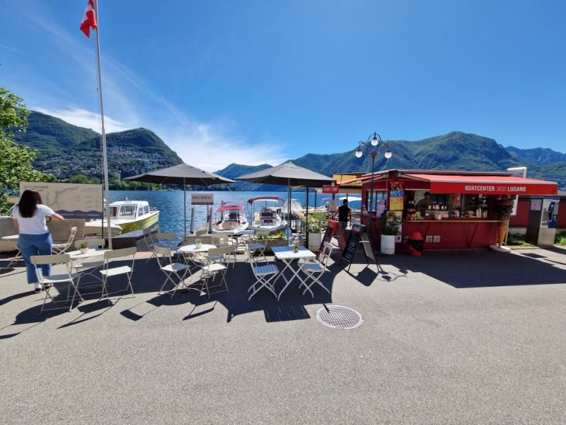 Una donna è in piedi davanti a una fila di tavoli e sedie vicino a un lago.