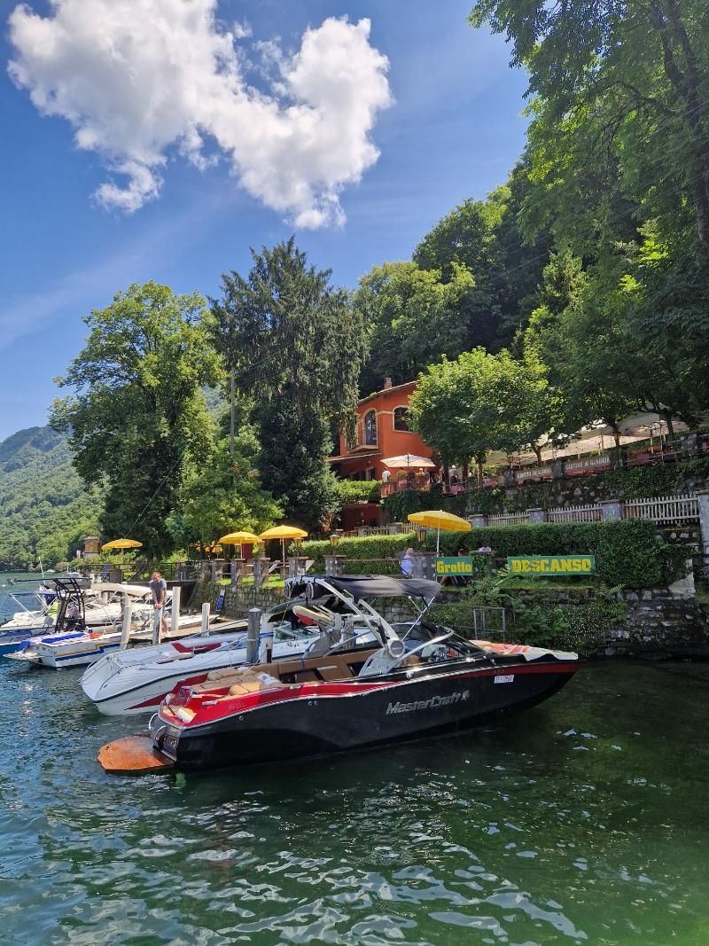 Un gruppo di barche è attraccato su un lago con una casa sullo sfondo.