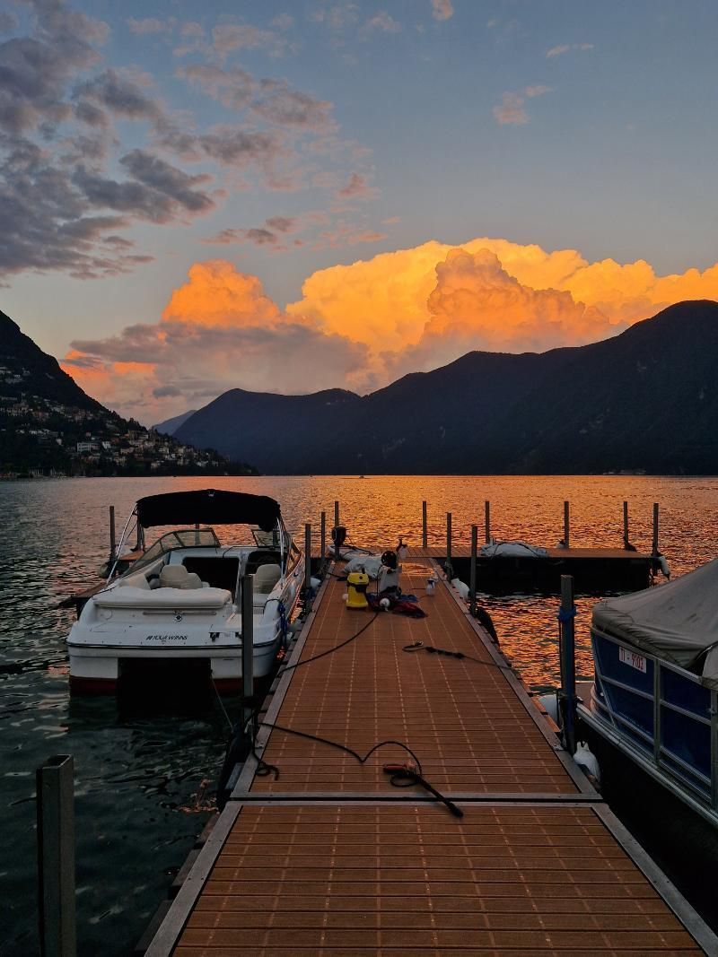 Un molo con barche attraccate al tramonto con le montagne sullo sfondo.
