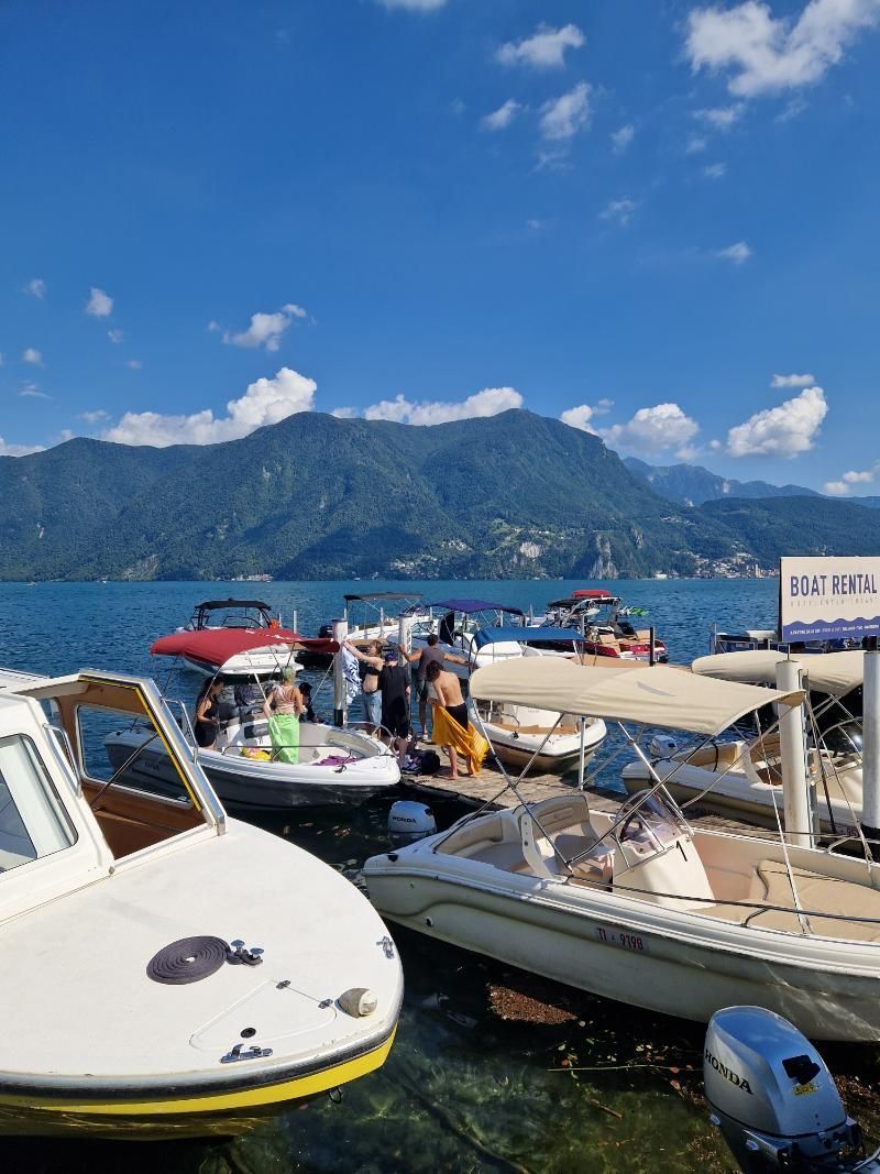 Un gruppo di barche è attraccato in acqua con le montagne sullo sfondo.