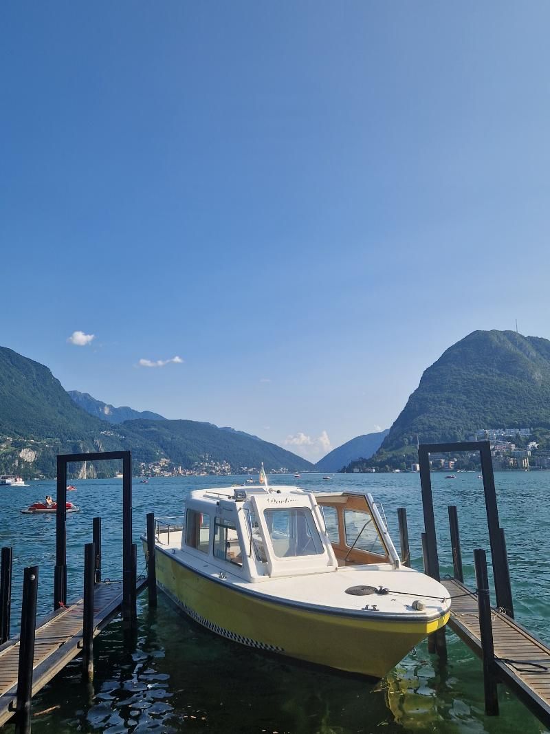 Una barca è attraccata a un molo in acqua con le montagne sullo sfondo.