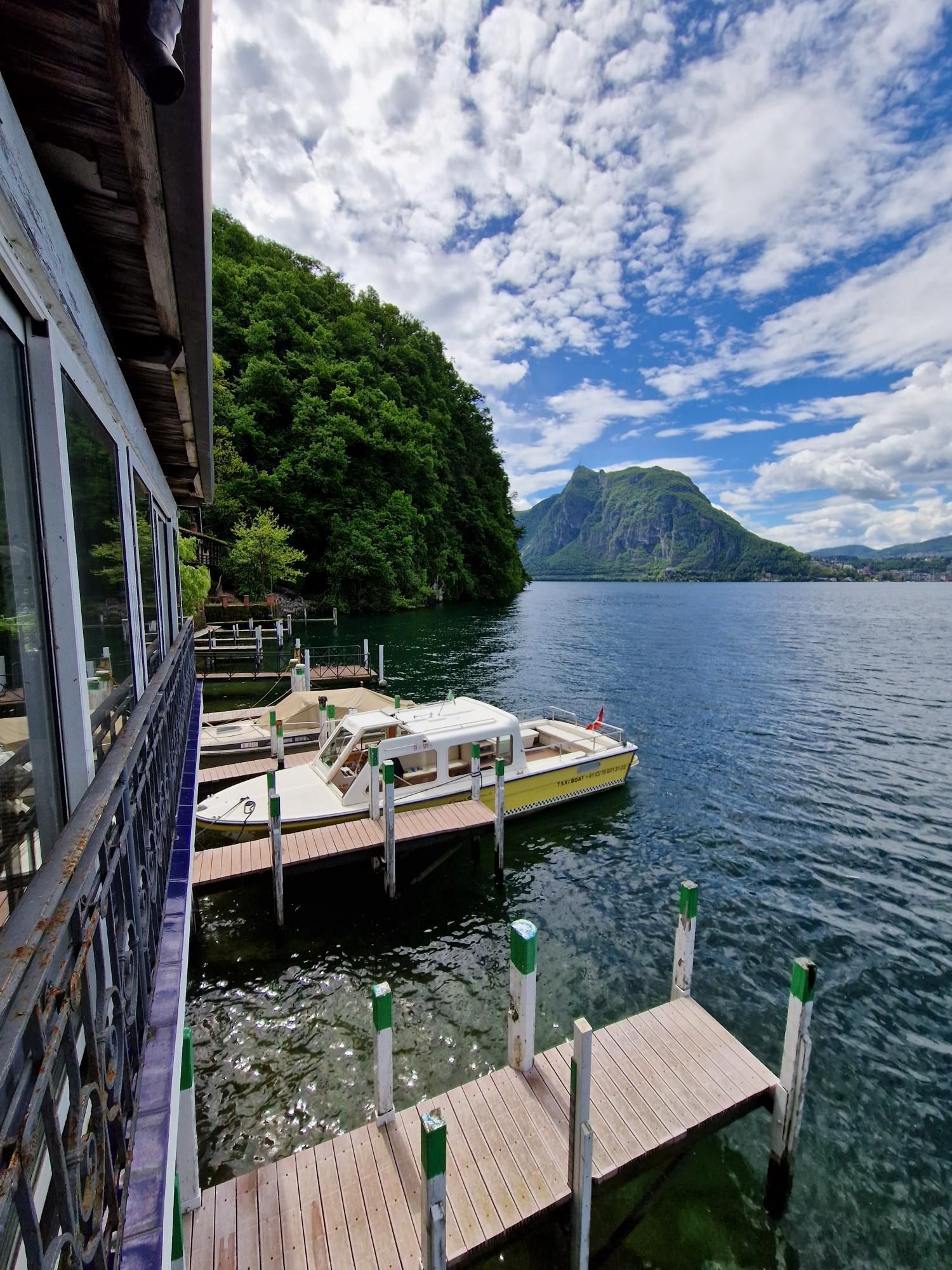 Una barca è attraccata a un molo su un lago con le montagne sullo sfondo.