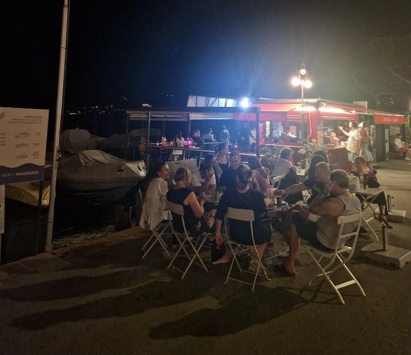 Un gruppo di persone è seduto ai tavoli fuori di notte