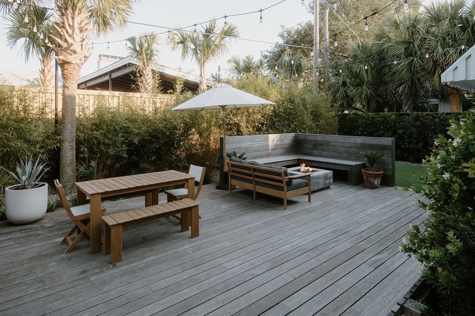 A wooden deck with a table , benches , chairs and umbrella.