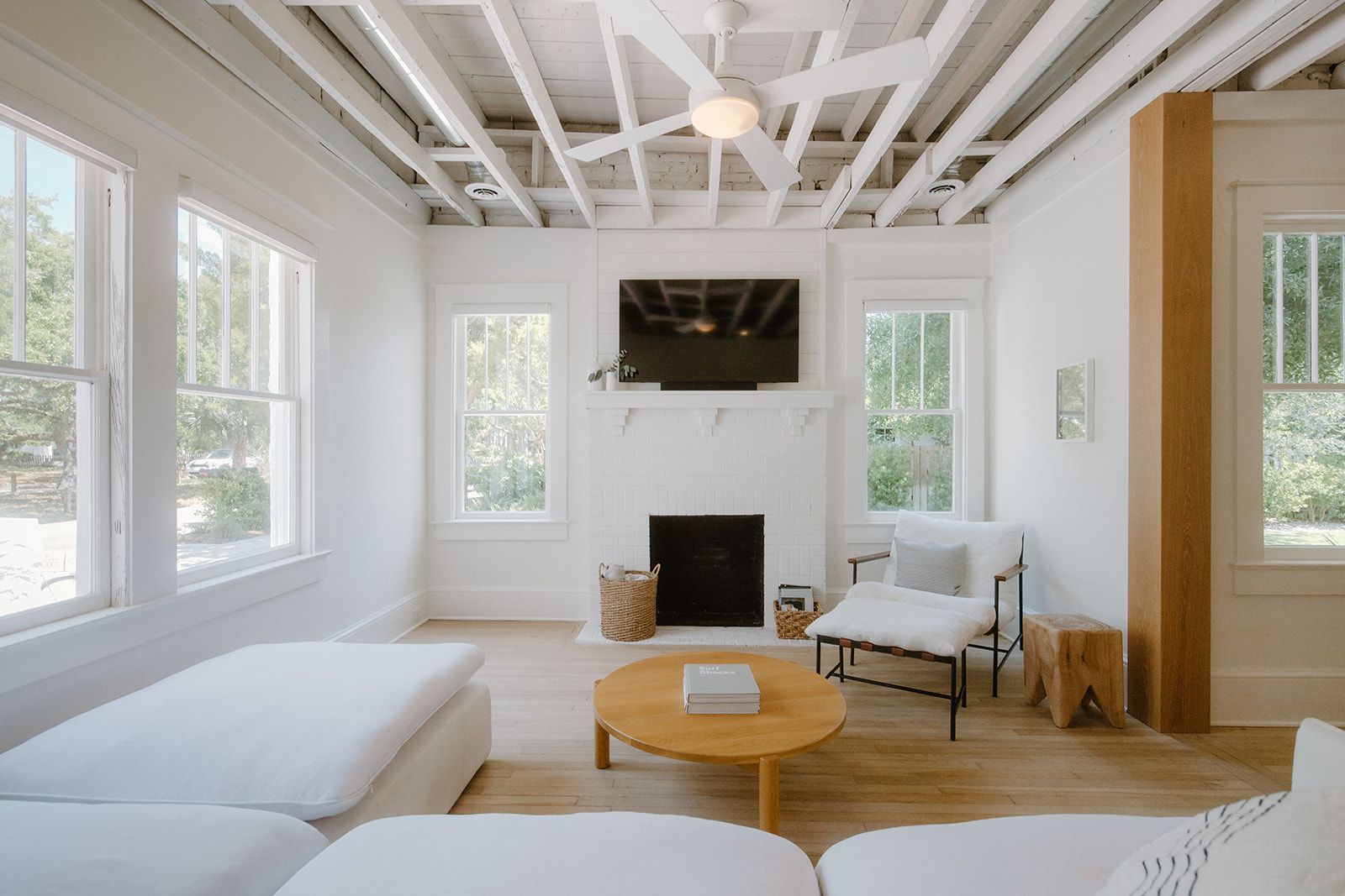 A living room with white furniture , a fireplace and a flat screen tv.