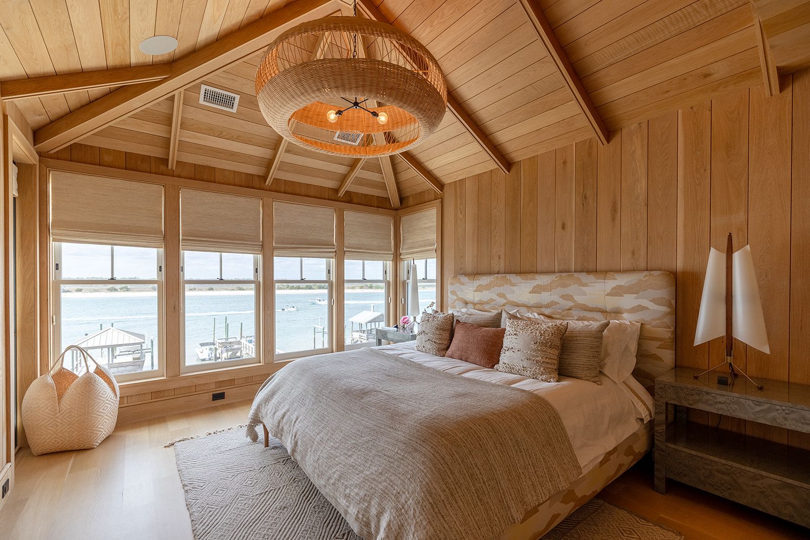 A bedroom with a bed , chair , nightstand and sliding glass doors with a view of the ocean.