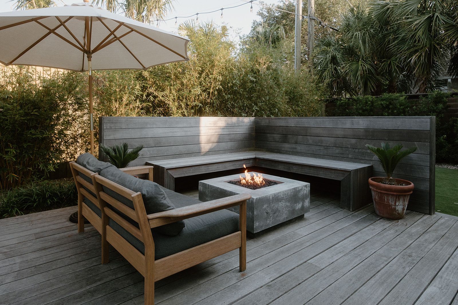 There is a fire pit on the deck with a couch and chairs.